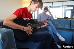 Ukrainian students Hlib Burtsev plays his guitar as Oleksii Shebanov sings along in the common area of their dorm ahead of their first year at Brown University in Providence, Rhode Island, U.S., August 16, 2022. (REUTERS/Brian Snyder)