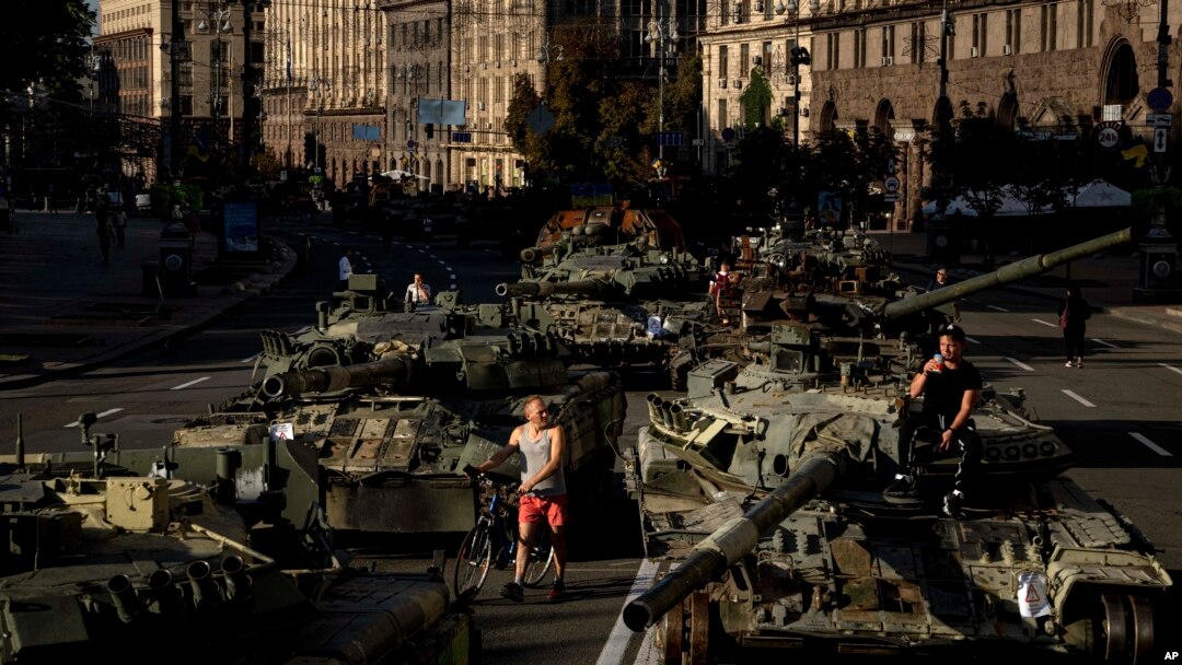 Sejumlah warga tampak berjalan di sekitar kendaraan militer milik Rusia yang hancur dan dipajang di pusat Kota Kyiv, Ukraina, pada 24 Agustus 2022. (Foto: AP/Evgeniy Maloletka)
