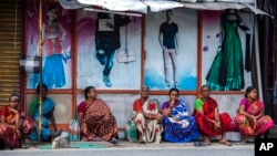 Tamil women sit by a roadside in the morning in anticipation of being hired for daily wage jobs in Kochi, southern Kerala state, India, Aug. 10, 2022.