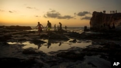 Egyptians on holiday walk at Cleopatra Beach, in the Mediterranean city of Marsa Matrouh, 270 miles (430 kilometers) northwest of the capital, Cairo, Egypt, Wednesday, Aug. 10, 2022. (AP Photo/Amr Nabil, File)