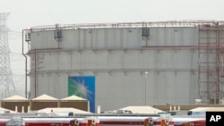 FILE - Fuel trucks line up in front of storage tanks at the North Jiddah bulk plant, an Aramco oil facility, in Jiddah, Saudi Arabia, March 21, 2021.