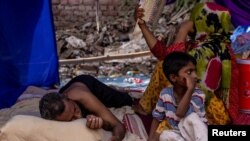 Sebuah keluarga pengungsi Rohingya beristirahat di tempat penampungan sementara setelah kebakaran menghancurkan kamp pengungsi Rohingya, New Delhi, India, 14 Juni 2021. (REUTERS/Danish Siddiqui)