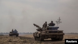 Ukrainian servicemen ride atop tanks near a front line in Mykolaiv region, as Russia's attack on Ukraine continues, Ukraine August 10, 2022.