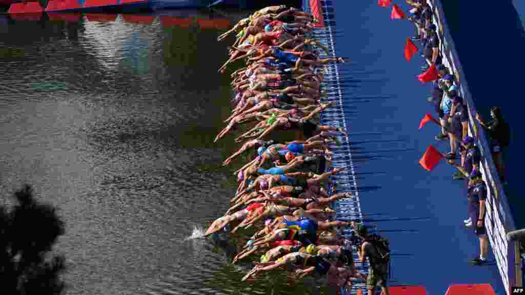 Athletes dive into the water at the start in the women's Elite Triathlon at the Olympic Park in Munich, Germany.