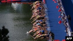 Athletes dive into the water at the start in the women's Elite Triathlon at the Olympic Park in Munich, Germany.