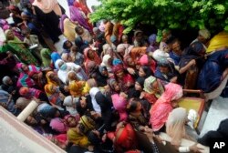 Flood affected people wait to receive for relief aid in Dadu district of Sindh Province in southern Pakistan, Saturday, Aug. 27, 2022. (AP Photo/Pervez Masih)