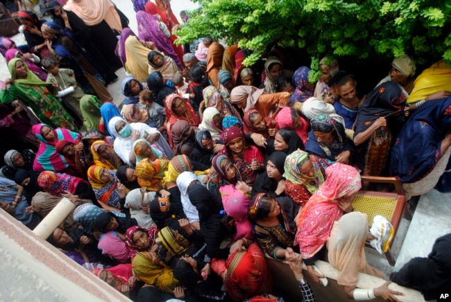 Flood affected people wait to receive for relief aid in Dadu district of Sindh Province in southern Pakistan, Saturday, Aug. 27, 2022. (AP Photo/Pervez Masih)