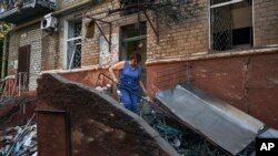 Žena čisti ispred stambene zgrade koja je oštećena nakon ruskog raketnog napada u Kramatorsku, istočna Ukrajina, 31.avgusta 2022.
