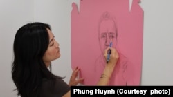 អ្នកស្រី Phung Huynh សិល្បៈករ​ផ្នែក​គំនូរ និង​សាស្ត្រាចារ្យ​ផ្នែក​សិល្បៈ​នៅ​មហា​វិទ្យាល័យ Los Angeles Valley គូរគំនូរនៅលើប្រអប់ខ្ចប់នំដូណាត់ពណ៌ផ្កាឈូក នៅក្នុងស្ទូឌីយោរបស់អ្នកស្រី។ (រូបថតផ្តល់ឲ្យដោយ Phung Huynh)