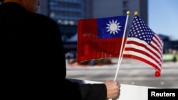 Seorang demonstran memegang bendera Taiwan dan Amerika Serikat untuk mendukung Taiwan di Burlingame, California. (Foto: Reuters)