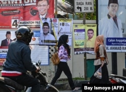 Pejalan kaki melewati spanduk kampanye Pemilu 2019 di Jakarta.(Foto: AFP/Bay Ismoyo)