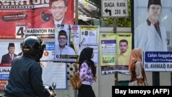 Pejalan kaki melewati spanduk kampanye Pemilu 2019 di Jakarta.(Foto: AFP/Bay Ismoyo)