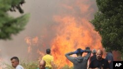 Warga setempat berdiri di dekat kebakaran hutan di Anon de Moncayo, provinsi Zaragoza, Spanyol, 13 Agustus 2022.