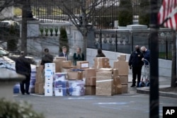 FILE - People wait for a moving van on Jan. 14, 2021, in Washington as Trump was preparing to leave the White House. (AP Photo/Gerald Herbert, File)