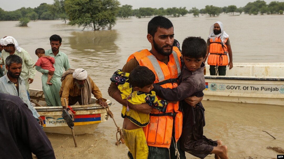 Des secouristes aident à évacuer les personnes touchées par les inondations de leurs maisons après les fortes pluies de mousson dans le district de Rajanpur, dans la province du Punjab, au Pakistan, le 27 août 2022.