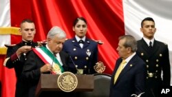 Presiden Andres Manuel Lopez Obrador (kiri) menerima selempang Kepresidenan Meksiko, didampingi Presiden Kongres, Porfirio Munoz Ledo, (tengah) dalam upacara pelantikan Presiden Meksiko di Kongres Nasional, Mexico City, Sabtu, 1 Desember 2018.