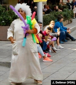 Clowns sell balloons to tourists in a Barcelona plaza: the biggest decision tourists have to make in Barcelona’s medieval Gothic Quarter each day is which restaurant to pick.
