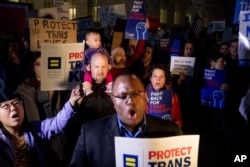 FILE - Activists and protesters with the National Center for Transgender Equality rally in front of the White House, Feb. 22, 2017, after President Donald Trump announced he would revoke some guidelines for protecting transgender student rights.