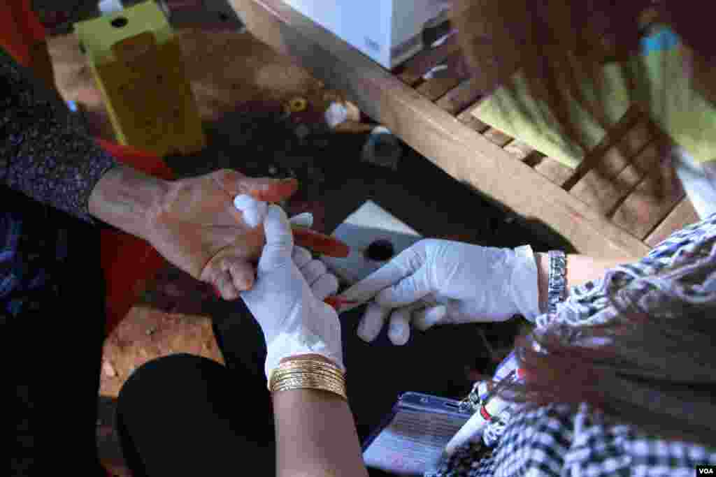 A Cambodian health agent pricks finger of an old lady who sought for HIV blood test service in Peam village, Muk Kompoul district, Kandal province, on Monday, Feb 22, 2016. (Photo: Aun Chhengpor/VOA Khmer)