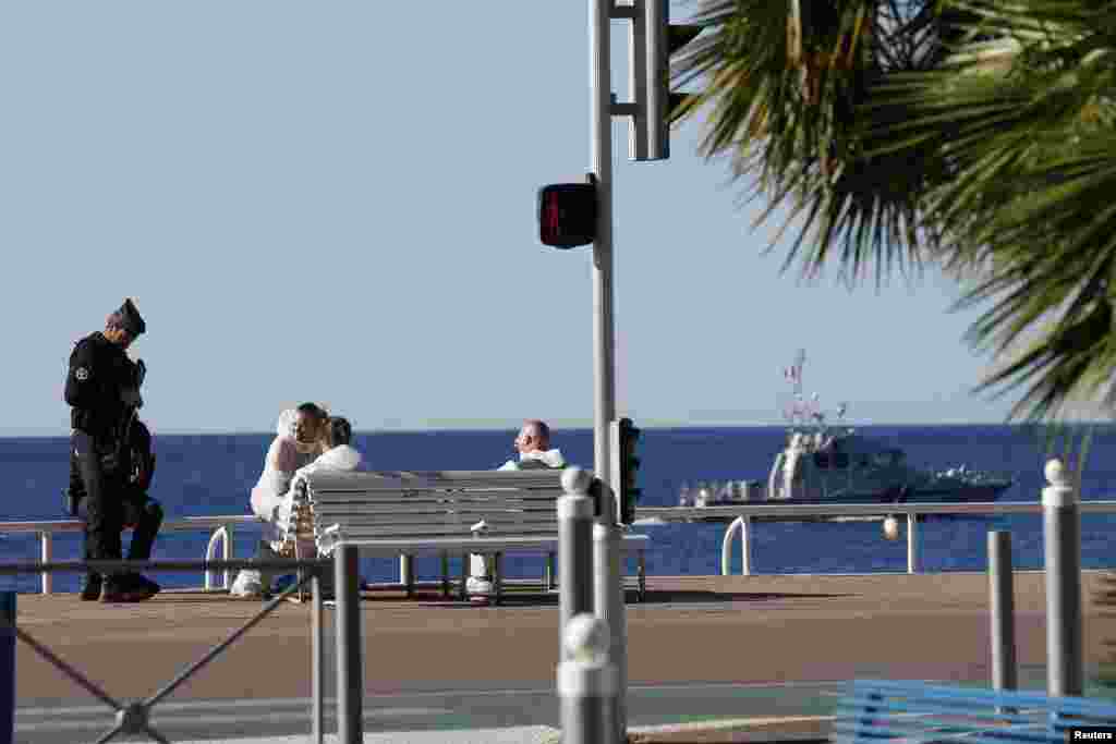 French police and investigators gather on the beachfront as a French Navy ship patrols the day after a truck ran into a crowd at high speed killing scores celebrating the Bastille Day July 14 national holiday on the Promenade des Anglais in Nice, France, 