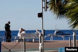 French police and investigators gather on the beachfront as a French Navy ship patrols the day after a truck ran into a crowd at high speed killing scores celebrating the Bastille Day July 14 national holiday on the Promenade des Anglais in Nice, France,