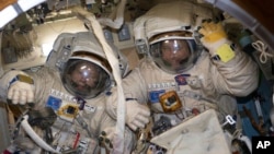 This Jan. 31, 2018 photo made available by NASA shows cosmonauts Alexander Misurkin, left, and Anton Shkaplerov in their Russian Orlan spacesuits during a fit check inside the International Space Station.