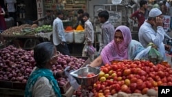 FILE - An Indian woman buys vegetables at a road side stall in New Delhi, Aug. 20, 2014. 