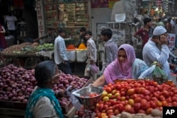 FILE - An Indian woman buys vegetables at a road side stall in New Delhi, Aug. 20, 2014.