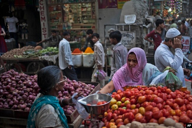 FILE - An Indian woman buys vegetables at a road side stall in New Delhi, Aug. 20, 2014.