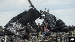 Pro-Russian fighters collect ammunition from the site of remnants of a downed Ukrainian army aircraft Il-76 at the airport near Luhansk, Ukraine, Saturday, June 14, 2014. 