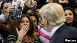 FILE - A woman blows a kiss to Republican presidential candidate Donald Trump (R) after Trump autographed her chest at his campaign rally in Manassas, Virginia, Dec. 2, 2015. 