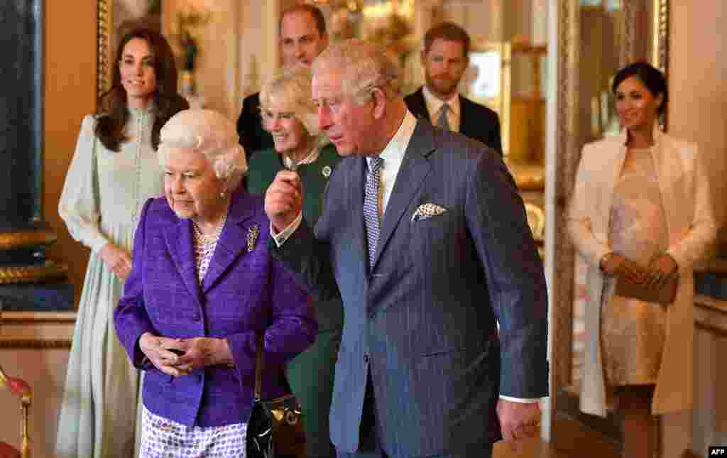 Britain's Prince Charles, Prince of Wales (C), walks with his mother, Britain's Queen Elizabeth II (2L), and his wife, Britain's Camilla, Duchess of Cornwall (3L), and his sons and their wives, Britain's Prince William, Duke of Cambridge (4L) and Britain's Catherine, Duchess of Cambridge (L), and Britain's Prince Harry, Duke of Sussex, (2R) and Meghan, Duchess of Sussex (R), during a reception to mark the 50th Anniversary of the investiture of the Prince of Wales at Buckingham Palace in London.