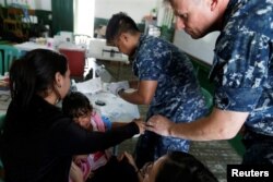 Kamila, daughter of Yenymar Vilches, a Venezuelan migrant, is attended by personnel of the ship of the United States Navy Hospital USNS Comfort at Divina Pastora High School in Riohacha, Colombia, Nov. 26, 2018.