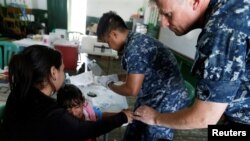 Kamila, daughter of Yenymar Vilches, a Venezuelan migrant, is attended by personnel of the ship of the United States Navy Hospital USNS Comfort at Divina Pastora High School in Riohacha, Colombia, Nov. 26, 2018.