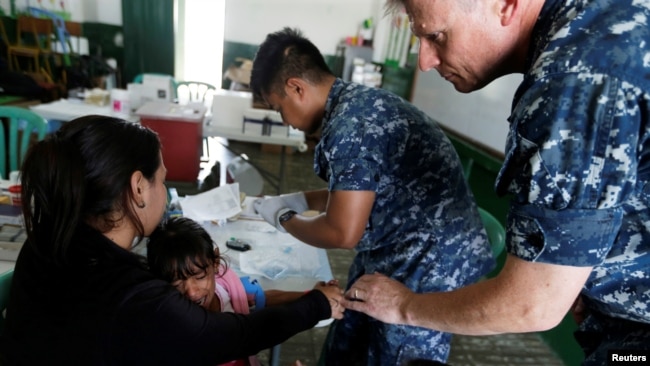 Kamila, daughter of Yenymar Vilches, a Venezuelan migrant, is attended by personnel of the ship of the United States Navy Hospital USNS Comfort at Divina Pastora High School in Riohacha, Colombia, Nov. 26, 2018.