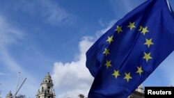 An anti-Brexit placard and EU flag are held aloft outside of the Houses of Parliament, in London, Britain, March 18, 2019. 