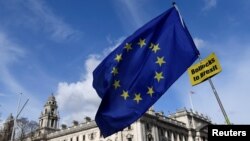 An anti-Brexit placard and EU flag are held aloft outside of the Houses of Parliament, in London, Britain, March 18, 2019. 