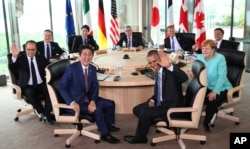 Japanese Prime Minsiter Shinzo Abe, foreground center left, and U.S. President Barack Obama, foreground center right, smile at photographers with other leaders of Group of Seven industrial nations, clockwise from left, French President Francois Hollande, British Prime Minister David Cameron, Canadian Prime Minister Justin Trudeau, European Commission President Jean-Claude Juncker, European Council President Donald Tusk, Italian Prime Minister Matteo Renzi and German Chancellor Angela Merkel, at the start of the second working session of the G-7 summit meetings in Shima, Mie Prefecture, Japan, Thursday, May 26, 2016.