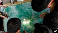 Myanmar Gems merchants examine a jade stone