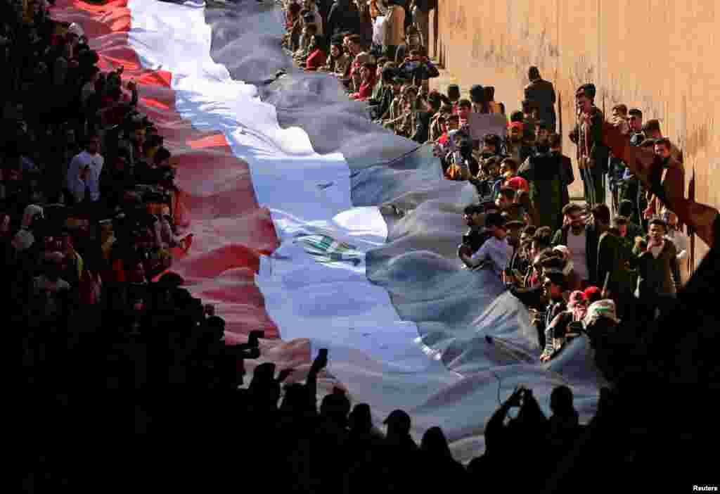 University students carry an Iraqi flag to express their rejection of the newly appointed Prime Minister of Iraq, Mohammed Tawfiq Allawi, during ongoing anti-government protests in Baghdad.