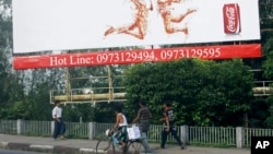 FILE - People walk under a huge advertising billboard of Coca-Cola in downtown Yangon, Myanmar.