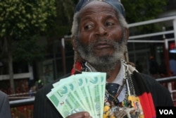 Holding bills of new Zimbabwean money, a man welcomes the introduction of bond notes saying the move will ease cash shortages in the country, in Harare, Zimbabwe, Nov. 28, 2016. (S. Mhofu/VOA)