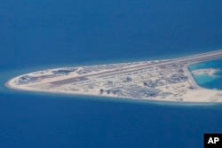 FILE - Chinese structures and an airstrip on the man-made Subi Reef at the Spratly group of islands in the South China Sea are seen from a Philippine Air Force C-130 transport plane of the Philippine Air Force, April 21, 2017.