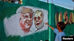 Seorang pria melukis di dinding gambar Presiden AS Donald Trump dan India Narendra Modi di Ahmedabad, India menjelang kunjungan Trump ke India (17/2). 
