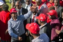 Leading opposition challenger Nelson Chamisa, left, waves at supporters as he arrives at a campaign rally in Bulawayo, Zimbabwe, July 21, 2018.