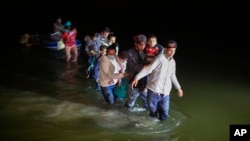 FILE - Migrant families from Central America wade through shallow waters toward Roma, Texas, March 24, 2021.