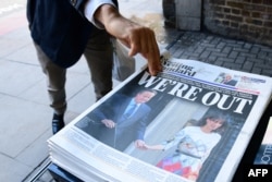 A man takes a copy of the London Evening Standard with the front page reporting the resignation of British Prime Minister David Cameron and the vote to leave the EU in a referendum, June 24, 2016.