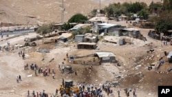 FILE - Palestinians gather around a bulldozer in Khan al-Ahmar, July 4, 2018. Israeli police scuffled with activists at a West Bank Bedouin community ahead of its planned demolition.