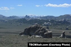Snow-capped mountains form a dramatic backdrop for the granite formations in the City of Rocks.