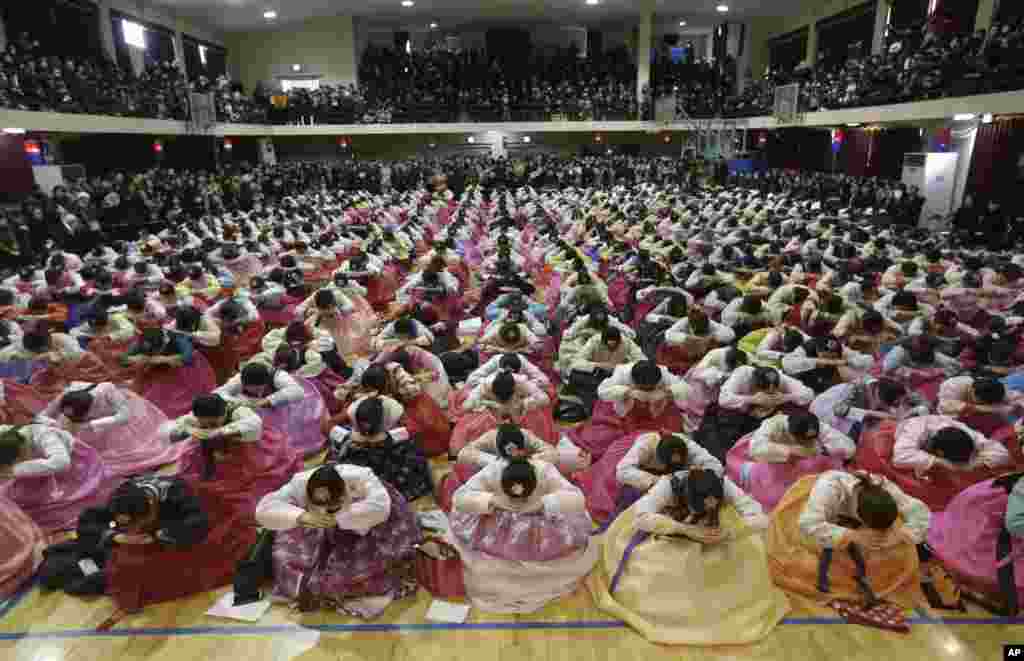 South Korean senior students clad in traditional costumes sit and bow during a joint graduation and coming-of-age ceremony at Dongmyung Girls&#39; High School in Seoul.
